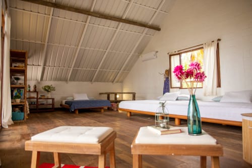 Amplio dormitorio de villa en Olamar Living con camas gemelas, muebles de madera, ventanas luminosas con flores rosas y vistas al mar