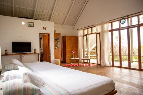 Amplio dormitorio de villa en Olamar Living con vistas al mar, TV, suelos de madera y puertas acristaladas que abren a terraza