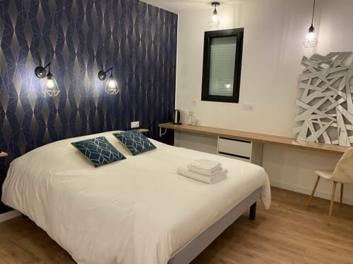 Chambre double moderne à La Maison Blanche B&B Bouguenais avec lit blanc, mur d'accent motif bleu marine et design contemporain