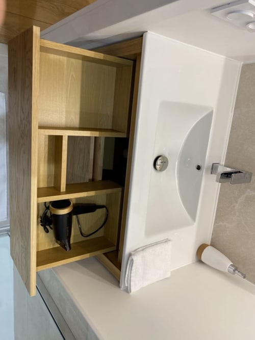 Mobile con ripiani in legno con bollitore nero nella camera La Maison Blanche Bouguenais, servizi bianchi visibili