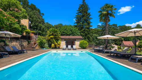 Luxe zwembad bij Domaine De Campagnac in Carsac-Aillac met ligbedden, parasols en stenen villa