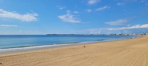 Plage de sable fin avec eaux océaniques calmes et skyline de la ville côtière, Sainte-Luce-sur-Loire