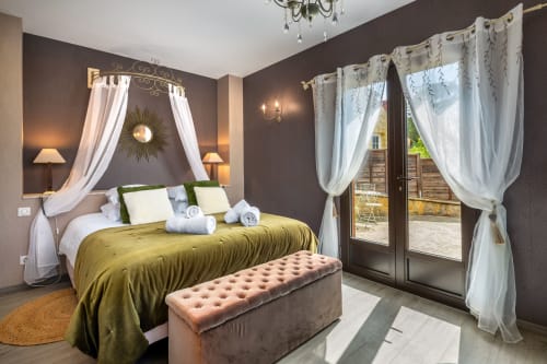 Luxe slaapkamer in Domaine De Campagnac met hemelbed, mosterdgele beddengoed en openslaande deuren met uitzicht op zwembad