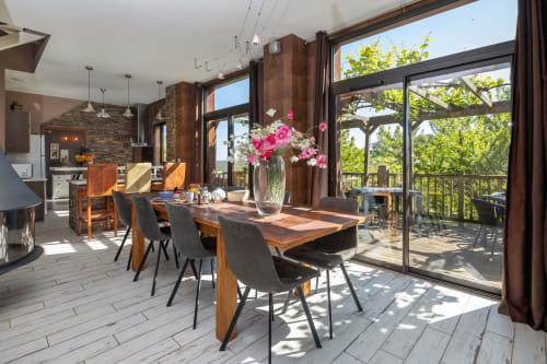 Heldere eethoek in gîte le Séchoir van Domaine De Campagnac met houten tafel, moderne stoelen, roze bloemen en