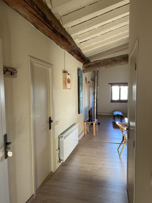 Pasillo luminoso de la habitación L'Isard en Casa Tapiolas B&B en Molló, Girona con vigas vistas y suelos de madera