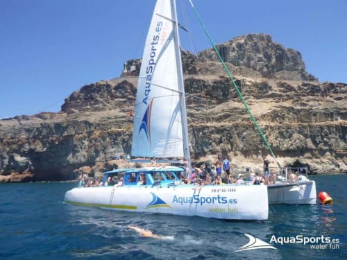 AquaSports catamaran sailing excursion near rocky cliffs in Arguineguín, Spain water activity