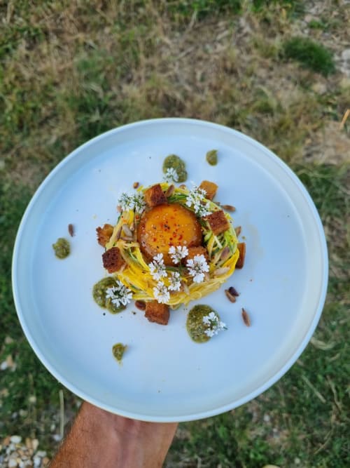 Assiette gastronomique avec œuf, pâtes, bacon, câpres et fleurs comestibles à la Maisonaurinko B&B à Thénon, France