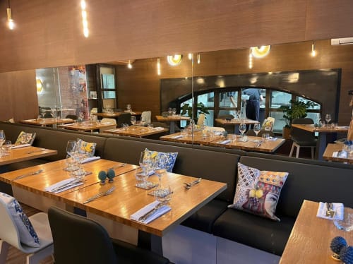 Salle à manger moderne du Mas D'en Ratéro B&B à Thuir avec tables en bois, banquettes noires et baies vitrées panoramiques.