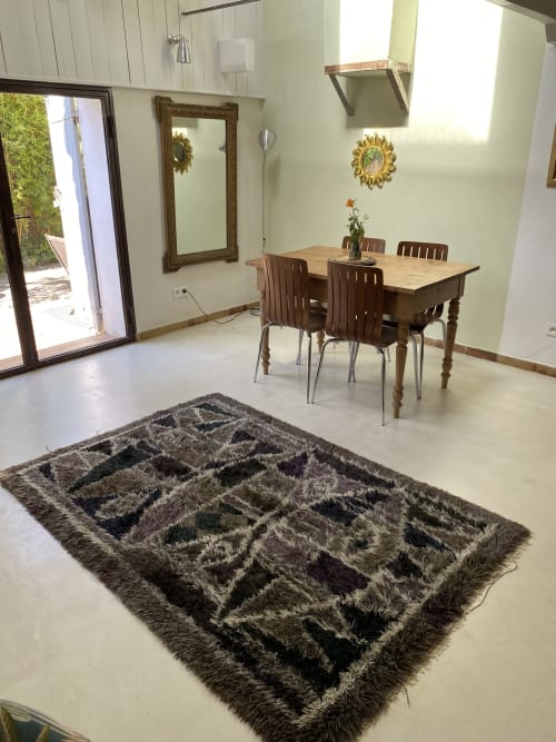Coin repas de l'appartement Bambou au Mas du Fort, Gargas avec table en bois, chaises, tapis motifs et terrasse avec vue sur le jardin