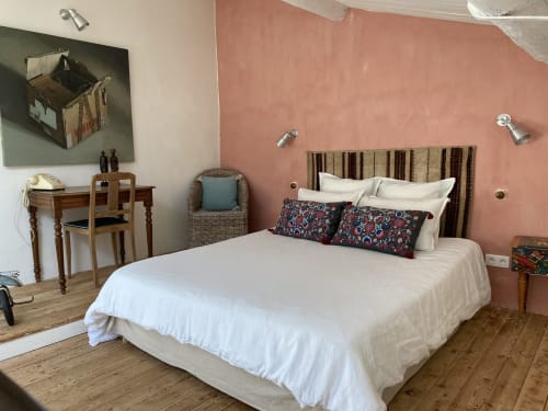 Chambre confortable de l'Appartement Bambou au Mas du Fort avec murs en terre cuite, tête de lit rayée et mobilier en bois