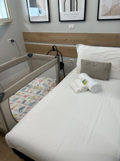 Camera familiare di Casa Lounge Istria Cagliari con letto matrimoniale, asciugamani arrotolati e lettino portatile