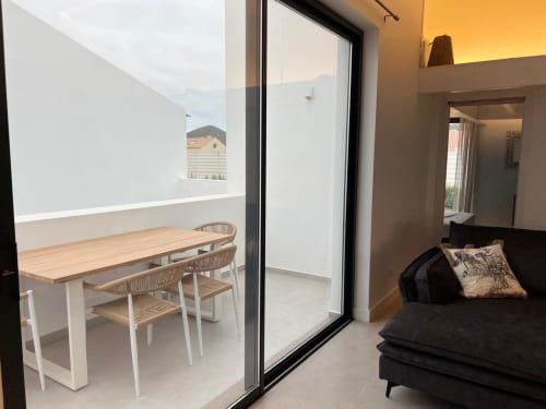 Vila Casa Furnas em Bordeira com sala integrada, mesa de jantar, sofá preto e vista para o mar da varanda privada