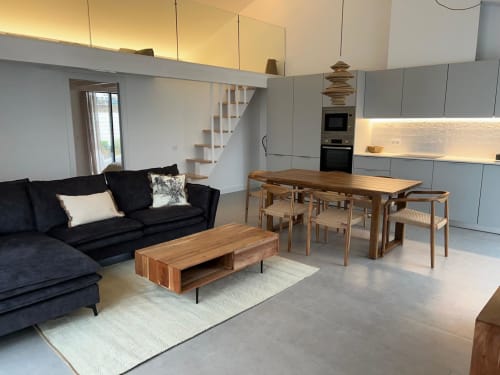 Sala de estar e jantar integrada na villa Casa Furnas com sofá preto, mesa de madeira, cozinha e escadas em Bordeira
