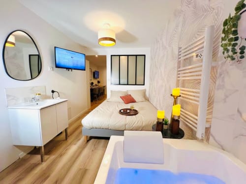 Modern studio apartment at Wellkhome in Bordeaux featuring bed, Jacuzzi tub, TV, and en-suite bathroom