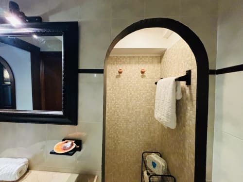 Baño moderno con entrada de ducha de marco negro arqueado, paredes de azulejos de mosaico, toallero blanco y espejo enmarcado en Holibai