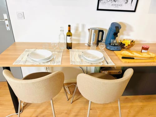 Dining area at Wellkhome Bordeaux apartment with set table, wine, kettle, and coffee machine