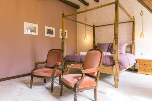 Chambre élégante avec lit à baldaquin doré, murs rose, fauteuils en bois et vue sur le jardin au gîte Le Prieuré Du Preux