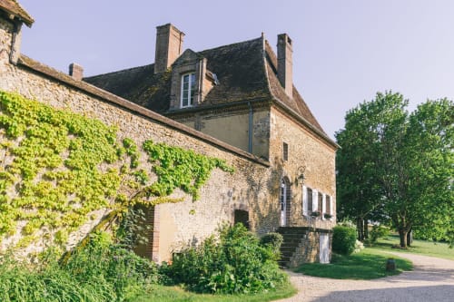 Historic stone cottage at Le Prieuré Du Preux with ivy-covered walls, mansard roof, and lush garden in Sépeaux, France
