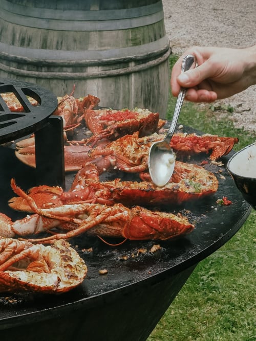 Grillade de homards au barbecue, dans un cadre rustique pour une expérience culinaire savoureuse et fraîche.