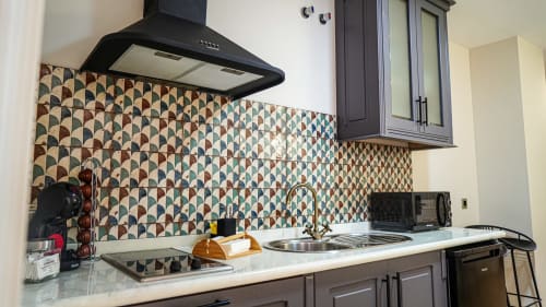 Cocina moderna en apartamento de Mérida con azulejos geométricos, campana negra y fregadero de acero inoxidable