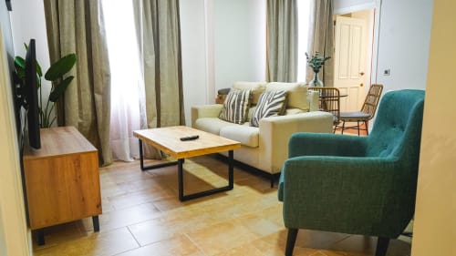 Moderno salón de apartamento en Mérida con sofá crema, butaca turquesa, mesa de café de madera y vistas a la ciudad