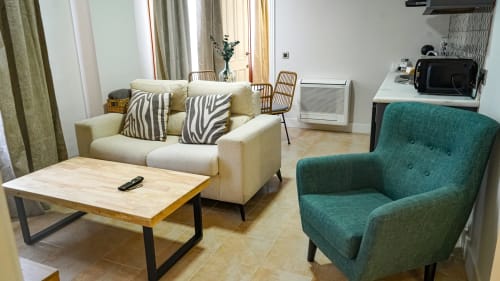 Sala de estar moderna en Mérida con sofá beis, butaca turquesa, mesa de café de madera y ventanales con vistas a la ciudad