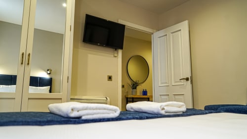 Apartamento hotel en Mérida con toallas dobladas cuidadosamente en la cama, espejo, televisor y paredes amarillas