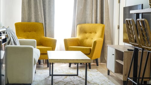 Sala de estar moderna en Mérida con sillones amarillos, sofá blanco y muebles contemporáneos