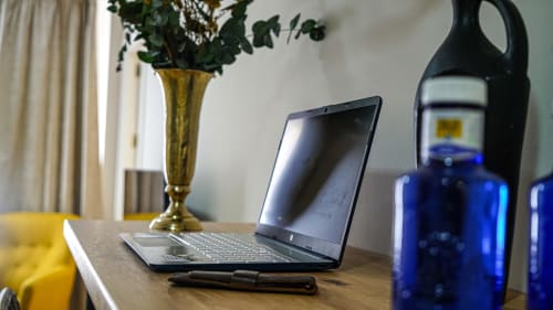 Espacio de trabajo en apartamento de Mérida con laptop, plantas de escritorio y botellas azules sobre mesa de madera