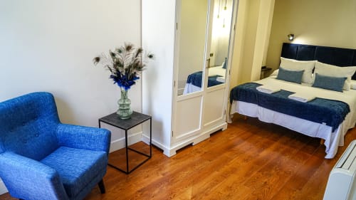 Dormitorio luminoso en Mérida con sillón azul, cama queen, pisos de madera y armario espejado