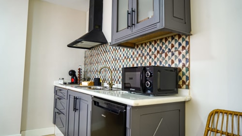 Moderna cocina en apartamento de Mérida con gabinetes grises, salpicadero geométrico, campana negra y electrodomésticos compactos.