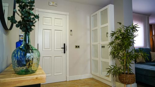 Entrada moderna de apartamento en Mérida con puertas blancas paneladas, pisos de madera, plantas decorativas y decoración minimalista