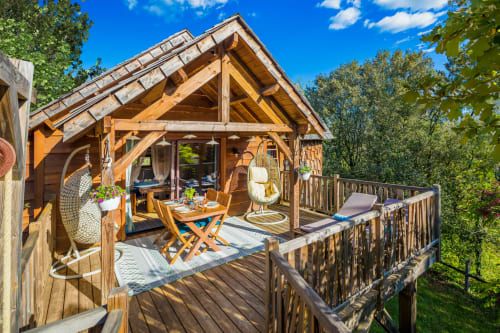 Béquia room luxury cabin with wooden terrace at Domaine De Campagnac, Carsac-Aillac, garden view with hanging chairs and