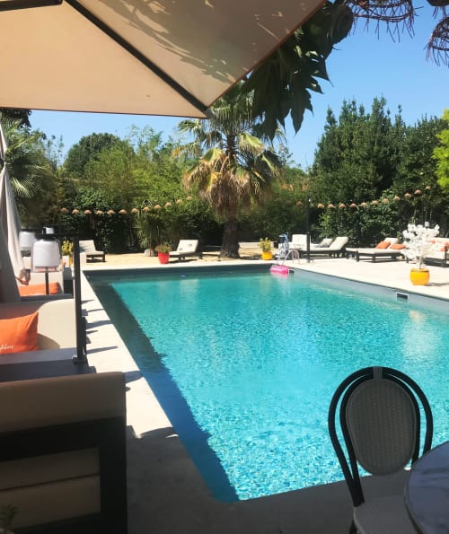 Espace piscine du Mes à Moi Pézenas avec eau turquoise, transats, palmiers et coin ombragé à Pézenas, France