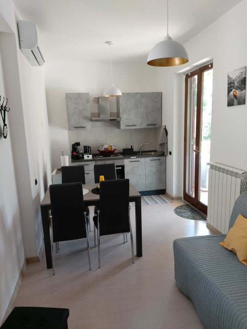 Moderna zona cucina-soggiorno dell'appartamento DAF HOUSE a Roccasecca con lampade a sospensione bianche, armadietti grigi e vista sulle montagne