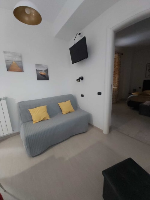 Moderno soggiorno a Roccasecca con divano grigio, cuscini gialli, TV a parete e arredamento con vista montagna.
