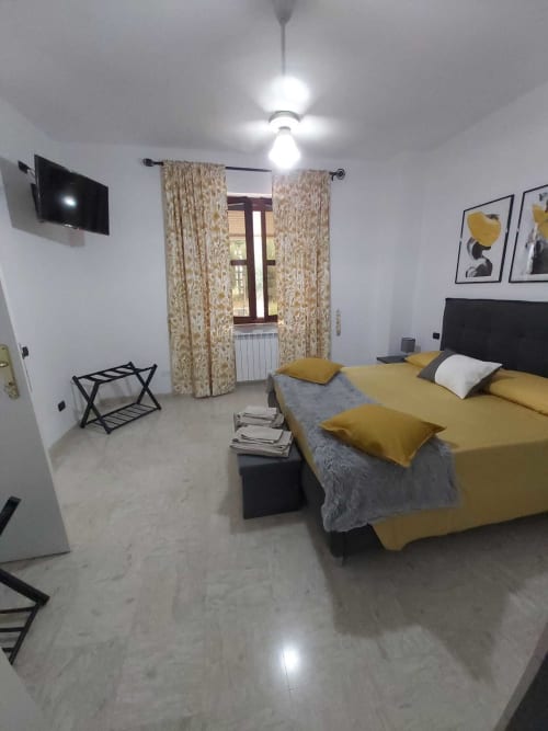 Camera moderna a DAF HOUSE Roccasecca con biancheria gialla, tende decorate, TV a parete e vista sulle montagne