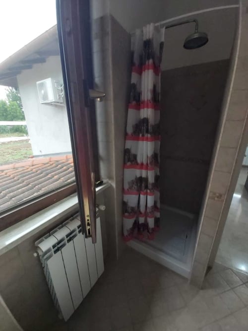 Bagno con doccia nell'appartamento DAF HOUSE a Roccasecca, camera con vista montagna e tende rosse a righe