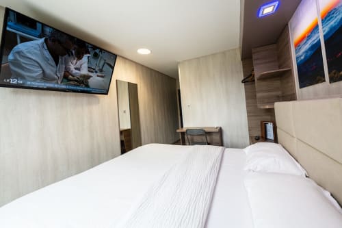 Habitació De Luxe a l'Hôtel Rocade Pamiers amb llit doble, TV penjada a la paret, escriptori i decoració moderna amb vista al jardí