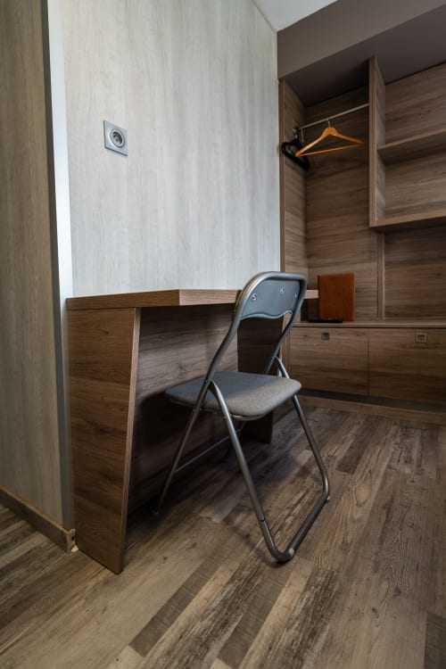 Espai de treball de la cambra deluxe a l'Hôtel Rocade amb escriptori de fusta, cadira plegable i armari a Pamiers