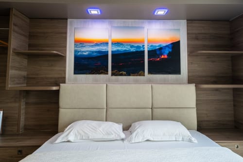 Habitació de luxe a l'Hôtel Rocade Pamiers amb capçal beige, coixins blancs i tríptic paisatge muntanyós posta de sol