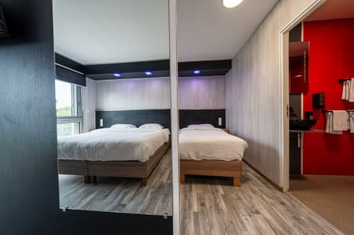 Habitació familiar a l'Hôtel Rocade de Pamiers amb armari amb mirall, dos llits, mobiliari modern i entrada vermella al bany