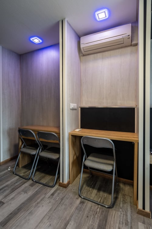 Raconet de treball modern a l'habitació familiar de l'Hôtel Rocade amb escriptori, cadires, llums LED blaves al sostre i aire acondicionat