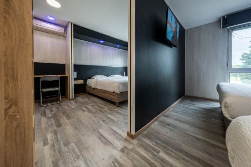 Habitació familiar moderna a l'Hôtel Rocade de Pamiers amb sòl de fusta, llits separats, TV i vistes a la ciutat