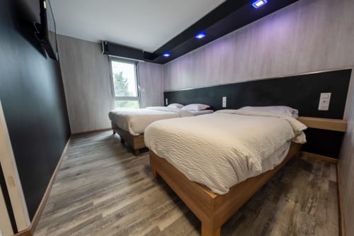 Habitació moderna a l'Hôtel Rocade Pamiers amb dos llits queen, paret d'accent fosca, sòl de fusta i vistes a la ciutat