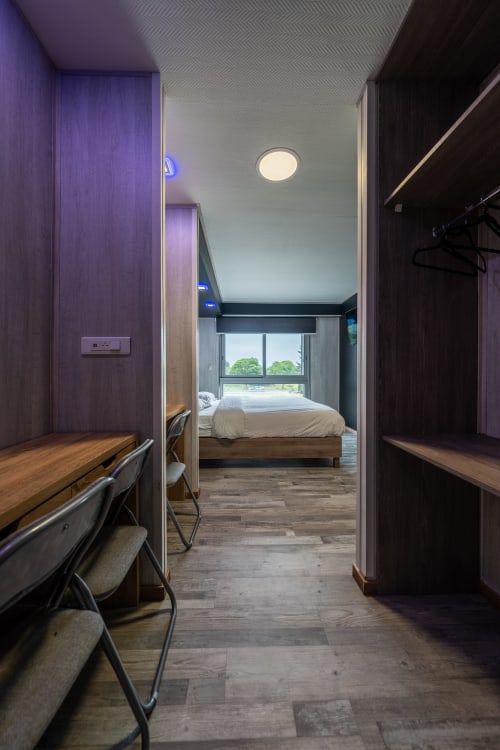 Habitació familiar moderna a l'Hôtel Rocade Pamiers amb escriptori, armari i vistes al dormitori amb jardí a través de grans finestres