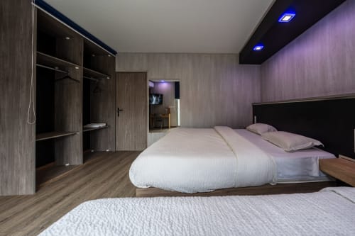 Habitació triple moderna a l'Hôtel Rocade a Pamiers amb llits dobles, armari de fusta fosca i il·luminació ambiental blava
