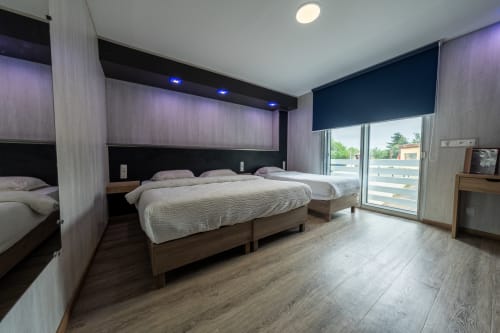 Habitació triple moderna a l'Hôtel Rocade de Pamiers amb dos lits, balcó amb vista a la ciutat i mobiliari contemporani