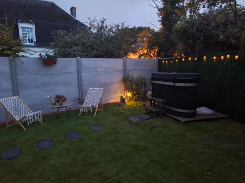 Jardin cottage au crépuscule avec chaises longues, foyer et ambiance chaleureuse à La Cour d'Hortense