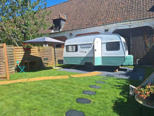 Caravane vintage menthe et blanche garée dans le jardin luxuriant de la maison d'hôtes La Cour d'Hortense, Sailly-Flibeaucourt